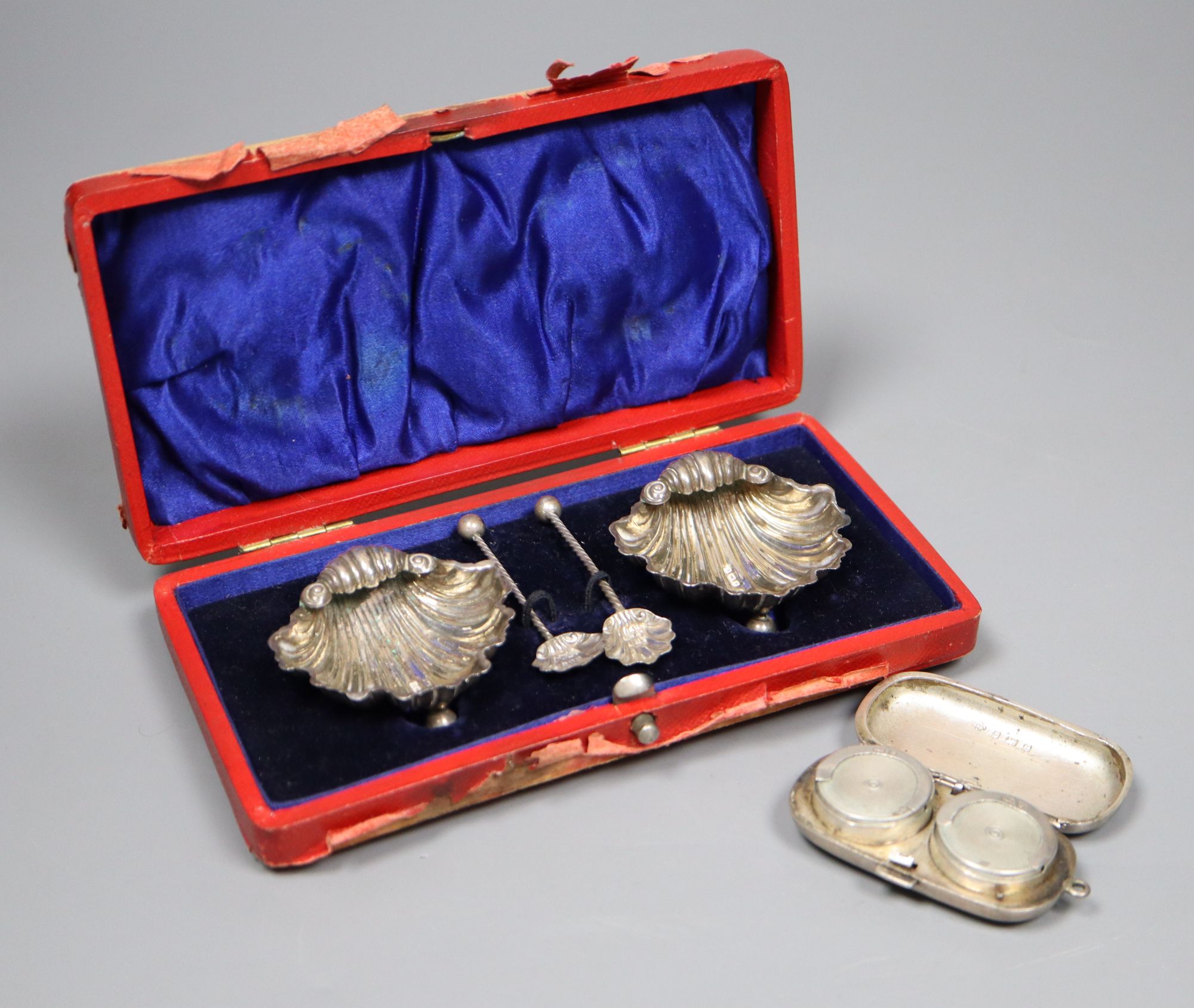 A pair of Edwardian silver shell salts and spoons and a similar twin compartment sovereign case, 61mm